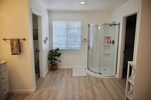 bathroom featuring hardwood / wood-style floors, vanity, an enclosed shower, and toilet