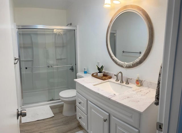 bathroom featuring vanity, hardwood / wood-style flooring, toilet, and an enclosed shower