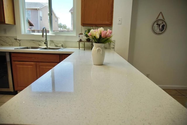 kitchen featuring light tile patterned floors, tasteful backsplash, beverage cooler, and sink