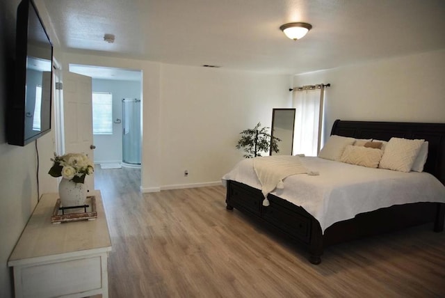 bedroom with hardwood / wood-style floors and ensuite bathroom