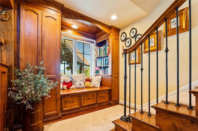 mudroom with crown molding and light colored carpet