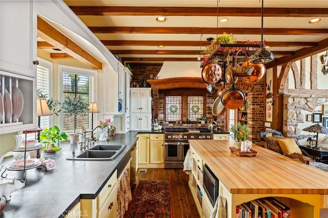 kitchen featuring dark hardwood / wood-style floors, beamed ceiling, appliances with stainless steel finishes, sink, and butcher block countertops