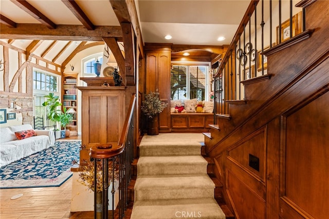 staircase featuring hardwood / wood-style floors, beamed ceiling, and high vaulted ceiling