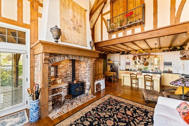 living room featuring beamed ceiling, a wood stove, hardwood / wood-style floors, and high vaulted ceiling