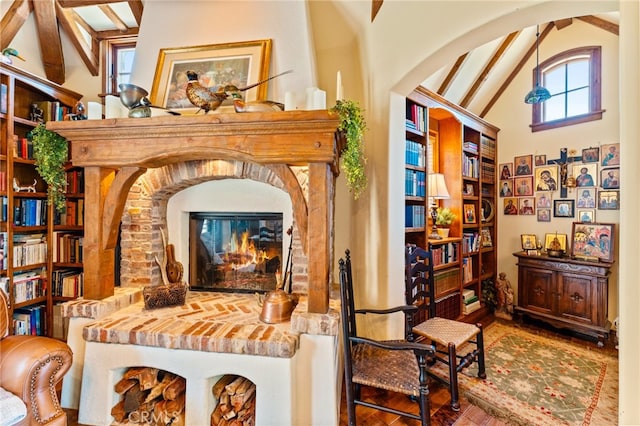 living area featuring beam ceiling, high vaulted ceiling, wood-type flooring, and a fireplace