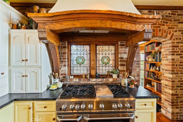 kitchen with brick wall, stainless steel stove, and wood-type flooring