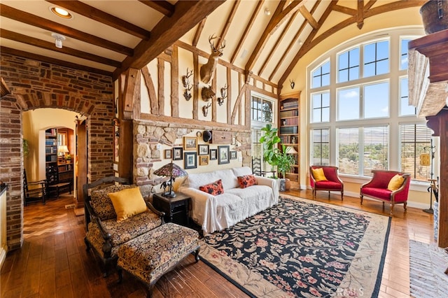 living area with beamed ceiling, a healthy amount of sunlight, high vaulted ceiling, and wood-type flooring