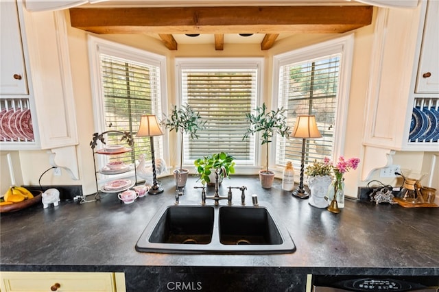 kitchen with white cabinetry, beamed ceiling, and sink