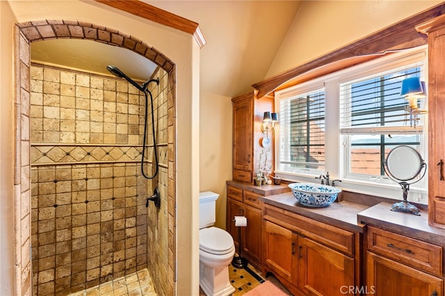 bathroom with lofted ceiling, a tile shower, toilet, vanity, and tile patterned flooring