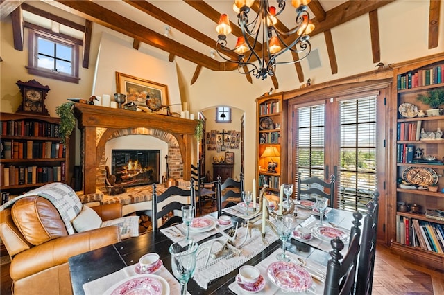 dining room featuring parquet floors, beamed ceiling, a chandelier, and a brick fireplace