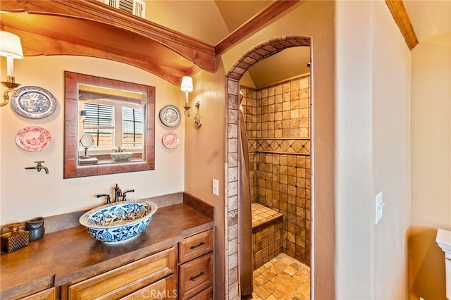 bathroom featuring a tile shower, tile patterned floors, vaulted ceiling, vanity, and crown molding