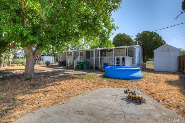 view of front facade with a patio area, central AC, a shed, and a swimming pool side deck