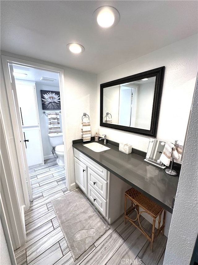 bathroom with vanity, wood-type flooring, and toilet