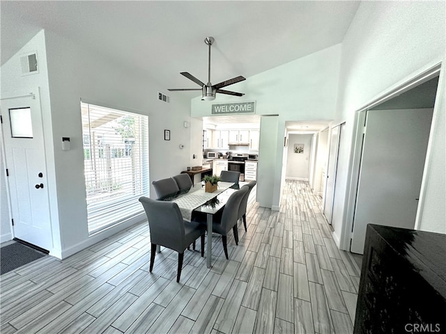 dining space with light hardwood / wood-style floors, high vaulted ceiling, and ceiling fan