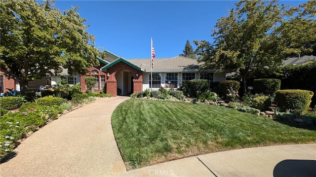 ranch-style home featuring a front yard, a tiled roof, and brick siding