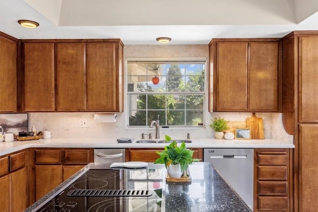 kitchen featuring dishwasher, tasteful backsplash, dark stone counters, and sink