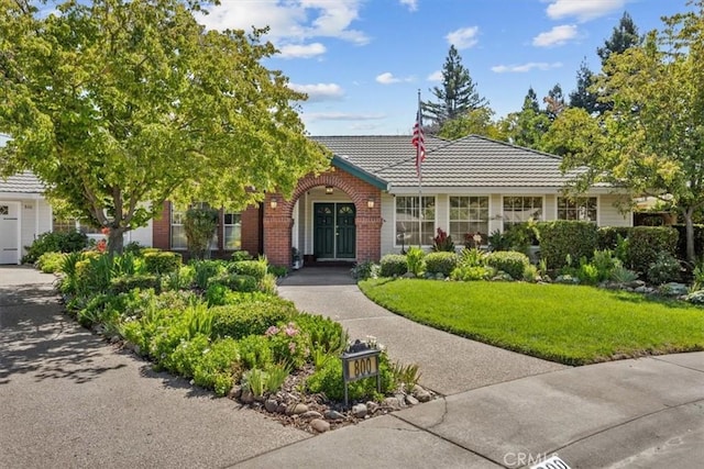 view of front of home with brick siding, a front lawn, and a tiled roof