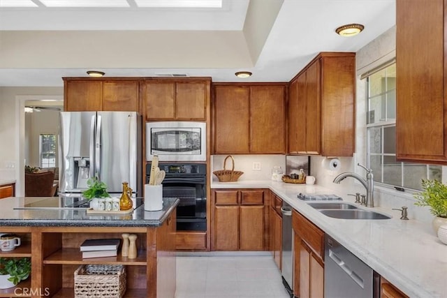 kitchen featuring black appliances, brown cabinetry, a sink, and open shelves