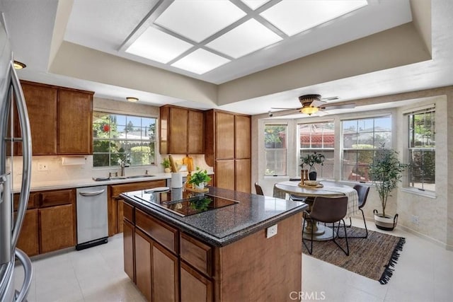 kitchen with a kitchen island, stainless steel refrigerator, sink, and a wealth of natural light