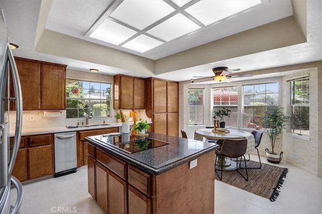 kitchen featuring a sink, black electric stovetop, stainless steel fridge, and a raised ceiling