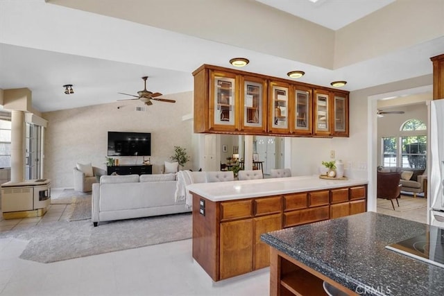 kitchen with black electric stovetop, light tile patterned flooring, kitchen peninsula, and a high ceiling