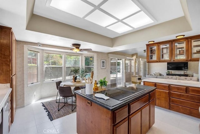kitchen with black electric stovetop, brown cabinets, glass insert cabinets, and a tray ceiling