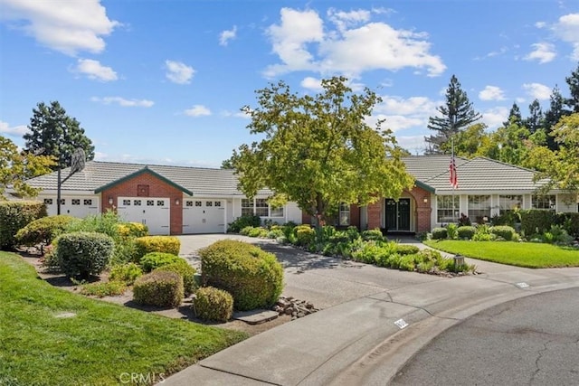 single story home with a tile roof, driveway, a garage, and a front lawn