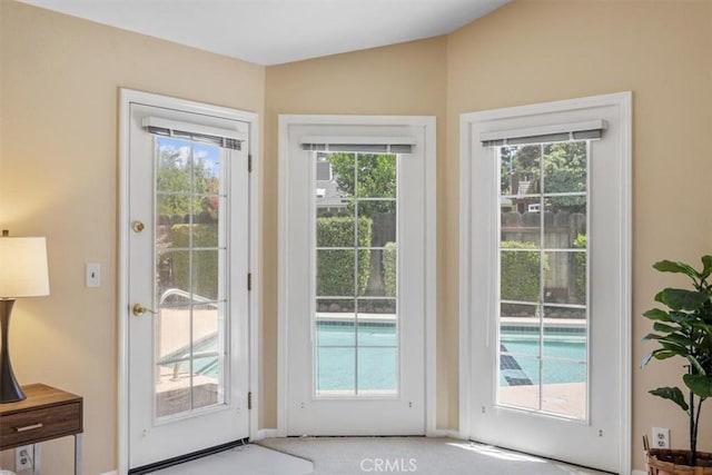 doorway with light carpet and lofted ceiling