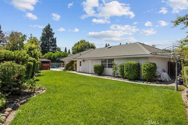 back of house featuring fence, stucco siding, a tiled roof, and a yard