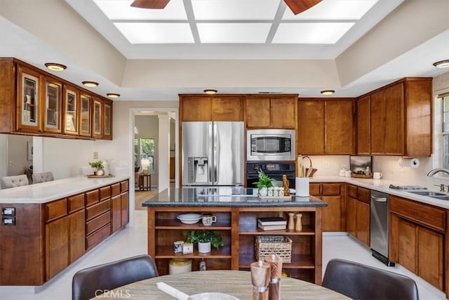kitchen with stainless steel appliances, a raised ceiling, glass insert cabinets, a sink, and open shelves