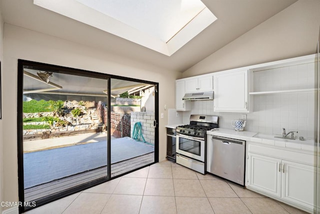 kitchen with plenty of natural light, white cabinetry, appliances with stainless steel finishes, and vaulted ceiling