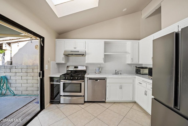 kitchen with white cabinets, appliances with stainless steel finishes, light tile patterned floors, and vaulted ceiling with skylight