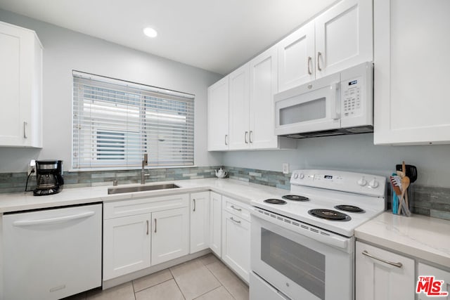 kitchen featuring light stone countertops, white appliances, sink, light tile patterned floors, and white cabinets