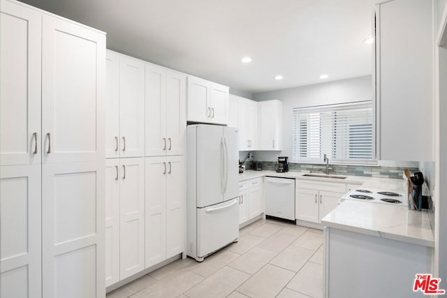 kitchen featuring white appliances, sink, light stone countertops, light tile patterned flooring, and white cabinetry