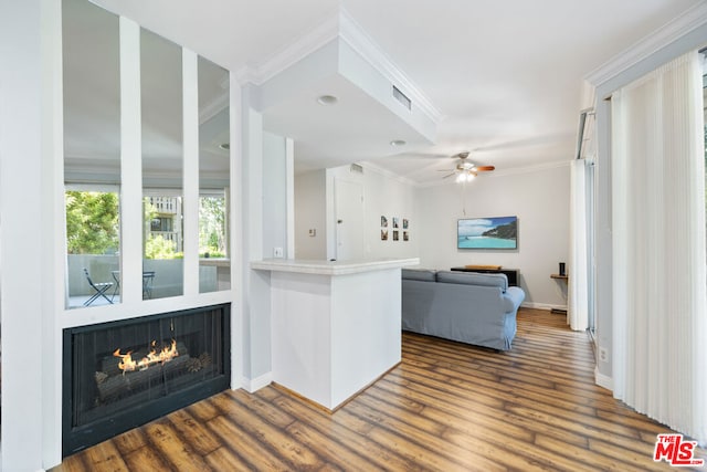 kitchen with kitchen peninsula, ceiling fan, crown molding, hardwood / wood-style flooring, and white cabinetry