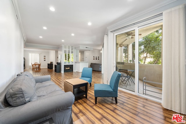 living room with ceiling fan, wood-type flooring, and ornamental molding