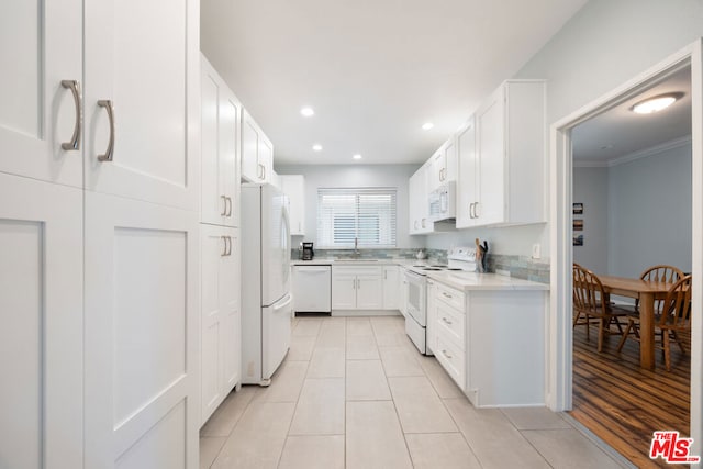 kitchen featuring white appliances, white cabinets, crown molding, sink, and light hardwood / wood-style flooring