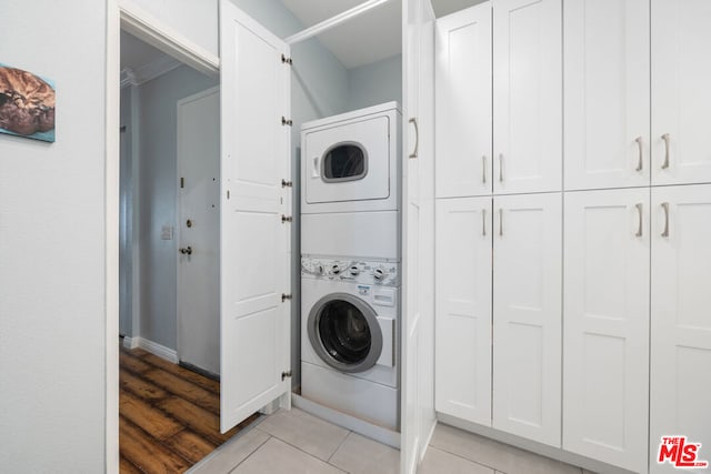 clothes washing area with stacked washing maching and dryer, light hardwood / wood-style flooring, and ornamental molding