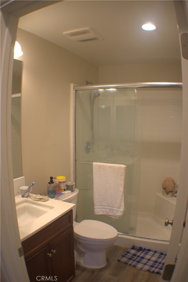 bathroom with a shower with shower door, toilet, wood-type flooring, and vanity