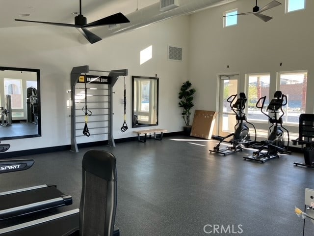 workout area with ceiling fan, plenty of natural light, and a towering ceiling