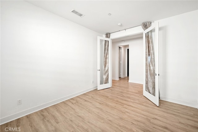 unfurnished room with french doors and light wood-type flooring