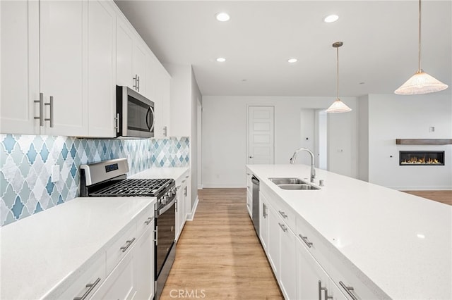 kitchen featuring hanging light fixtures, white cabinetry, sink, and appliances with stainless steel finishes