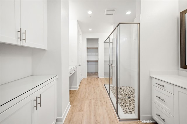 interior space with walk in shower, vanity, and hardwood / wood-style flooring