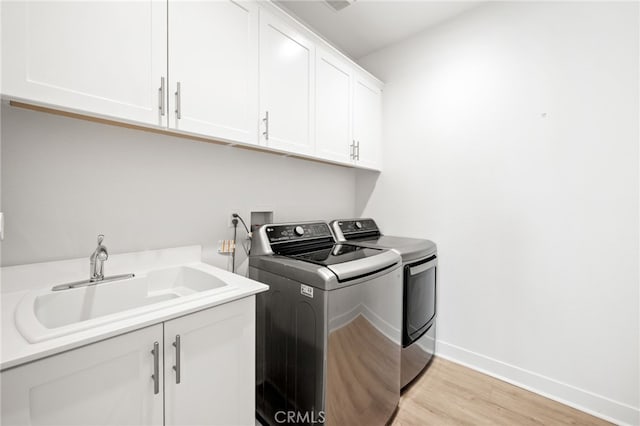 clothes washing area with cabinets, independent washer and dryer, sink, and light hardwood / wood-style flooring