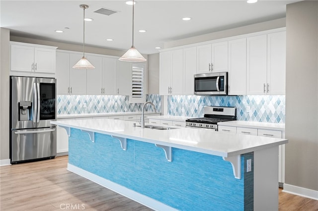 kitchen with sink, stainless steel appliances, and an island with sink