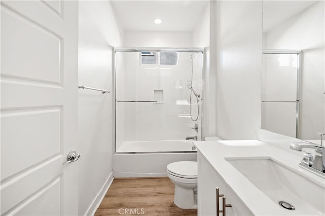 full bathroom with hardwood / wood-style floors, vanity, toilet, and enclosed tub / shower combo