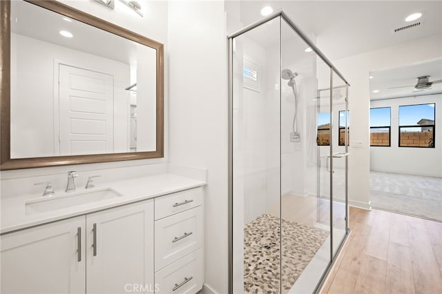 bathroom with walk in shower, ceiling fan, vanity, and hardwood / wood-style flooring