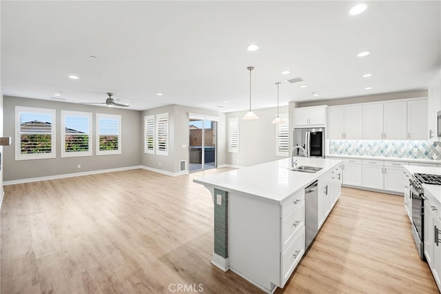 kitchen featuring white cabinetry, sink, ceiling fan, a center island with sink, and appliances with stainless steel finishes