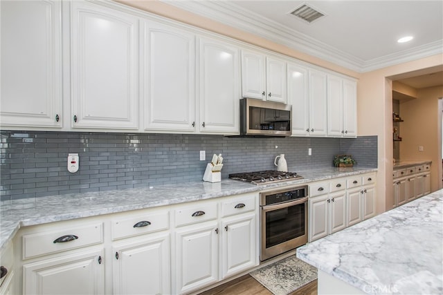 kitchen featuring white cabinets, stainless steel appliances, hardwood / wood-style floors, and tasteful backsplash