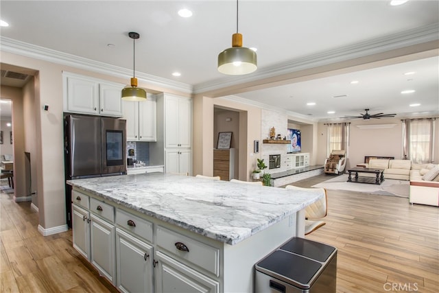 kitchen with light wood-type flooring, white cabinetry, a kitchen island, decorative light fixtures, and ceiling fan